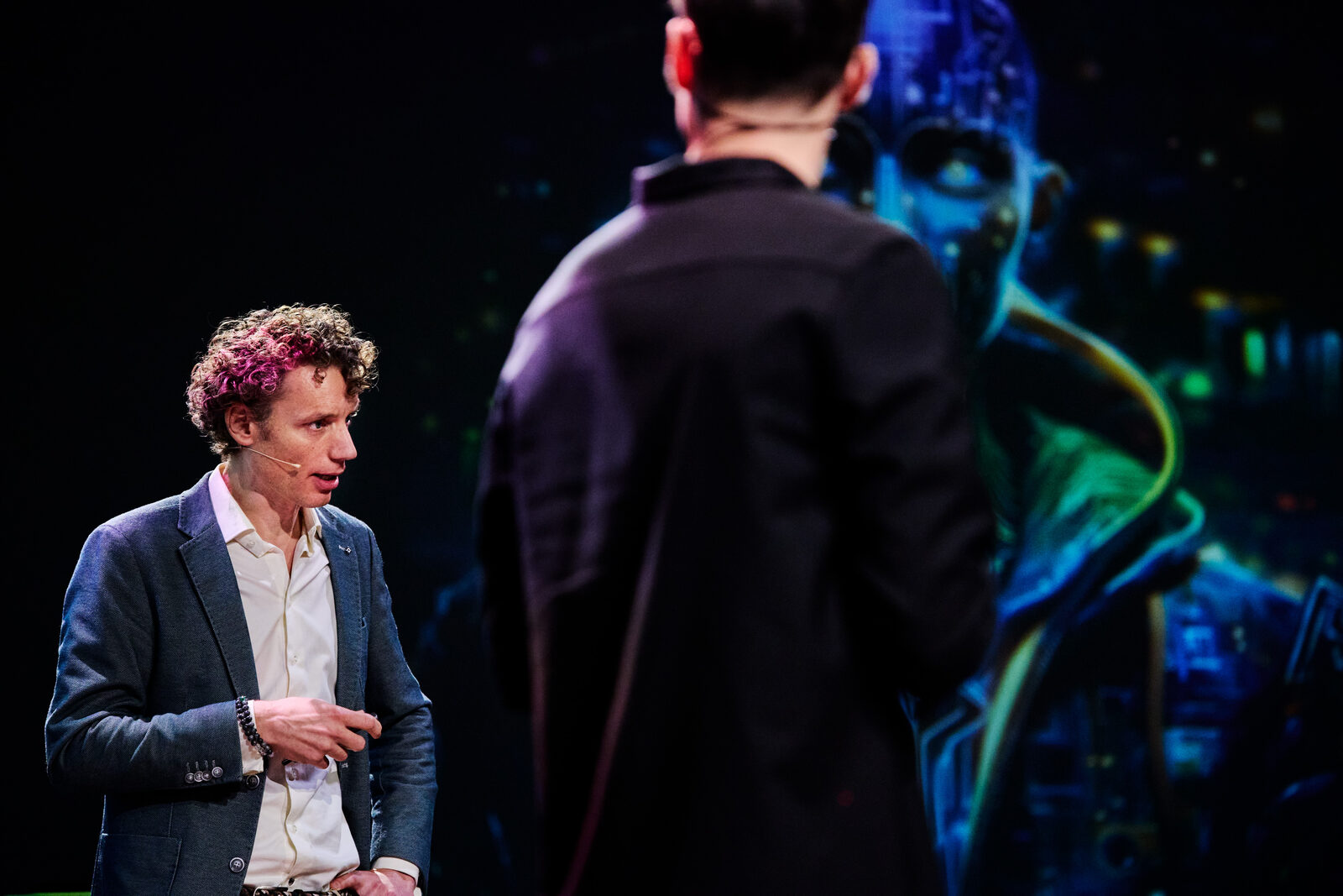 Laurens Waling in gesprek op het podium, naast een groot scherm met datavisualisatie